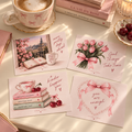 Vier JOSIE APRIL Postkarten mit rosa Kaffeetasse, Büchern und Kirschen auf hellem Tisch